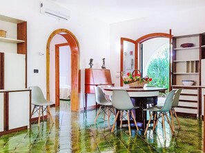 A dining area with a round table, chairs, and a view through an open door. - Orchidea by Interhome (Siracusa)