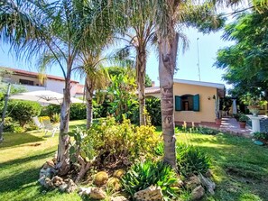 A residential property with a well-maintained garden, palm trees, and a house with a red roof. - Orchidea by Interhome (Siracusa)
