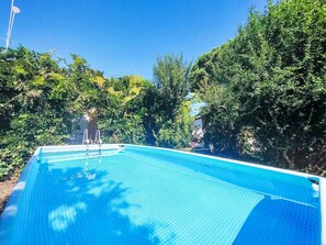 A rectangular swimming pool with a clear blue surface, surrounded by dense green foliage. - Orchidea by Interhome (Siracusa)