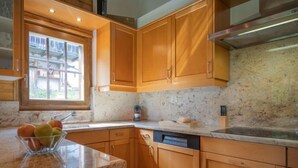 A kitchen with wooden cabinets, a granite countertop, a window, and a dishwasher. - Falaises by Interhome (Ovronnaz)