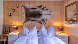 Ein Schlafzimmer mit einem Bett, zwei Nachttischen, einer Holzwand und einem aufgehängten Tierkopf.