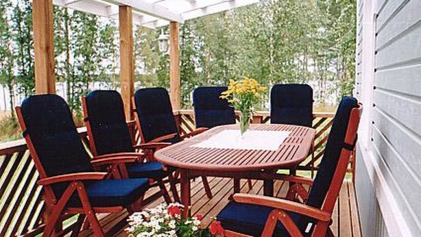 A covered outdoor seating area with a round wooden table and six chairs. - Eteläranta by Interhome (Hankasalmi)