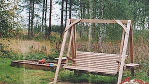A wooden swing set in a garden with a tractor and flowers. - Eteläranta by Interhome (Hankasalmi)