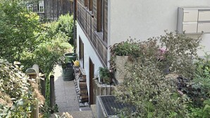 A narrow alleyway with a gravel path, wooden fence, and various plants. - Am Ryschbächli by Interhome (Zweisimmen)