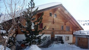 A wooden chalet with a sloped roof, a wooden porch, and a snow-covered ground. - Am Ryschbächli by Interhome (Zweisimmen)