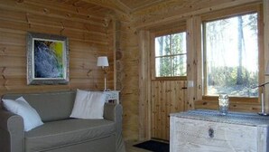 A wooden cabin interior with a sofa, a small table, and a window.