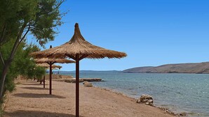A beach with thatched umbrellas and pine trees. - Melandura by Interhome (Pag/Dinjiška)