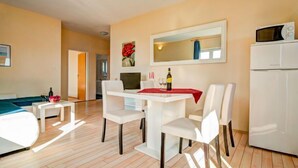 A modern hotel room with a bed, a dining area with a table and chairs, a microwave, and a refrigerator. - Melandura by Interhome (Pag/Dinjiška)