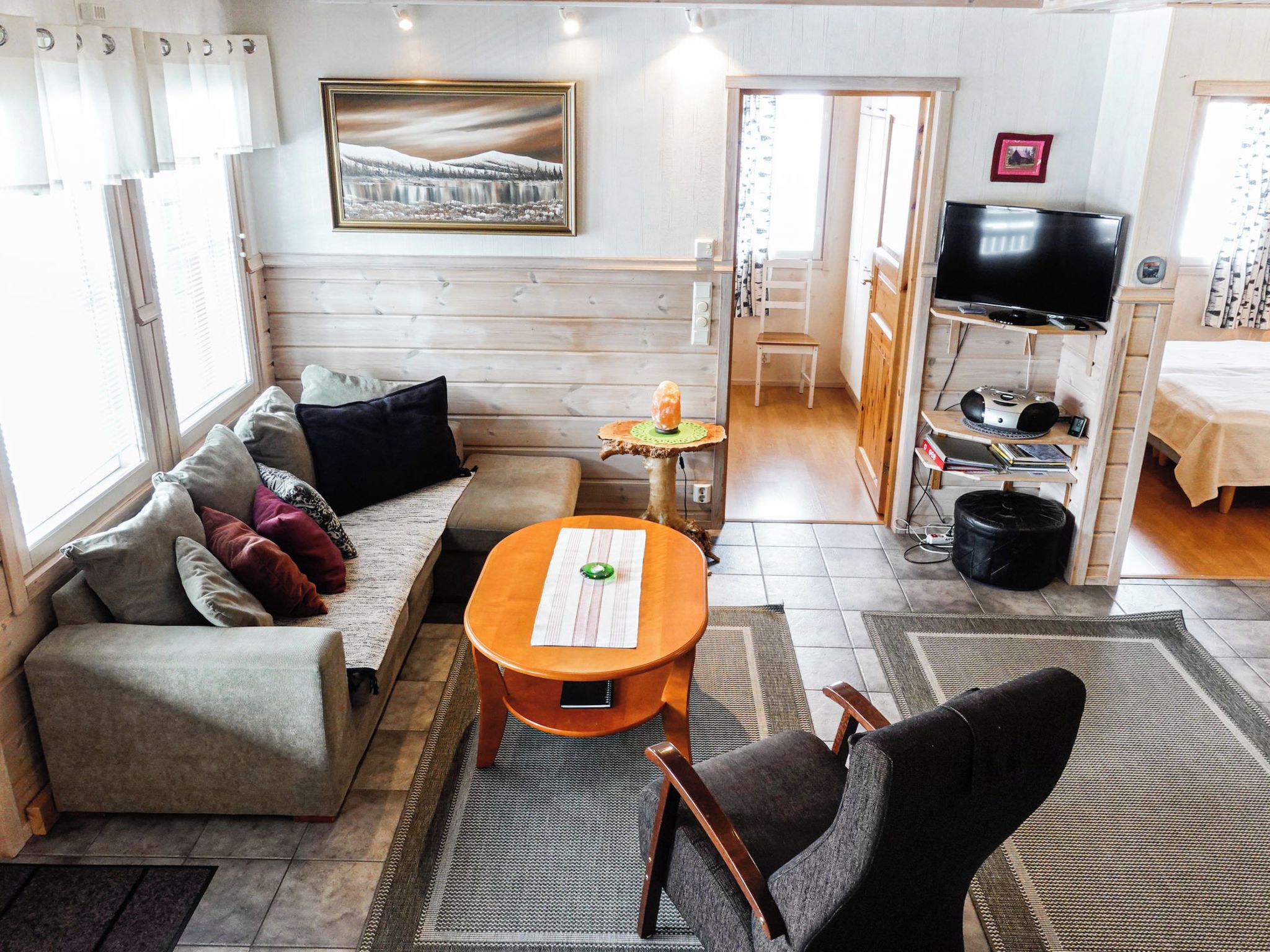A cozy living room with a sofa, a small table, a television, and a painting on the wall.