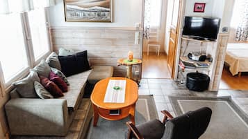 En hyggelig stue med sofa, et lille bord, fjernsyn og et billede på væggen.