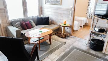 A cozy living room with a sofa, a coffee table, a TV, and a small table with a candle.