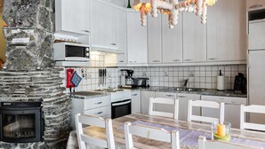 A modern kitchen with white cabinets, a stone wall, a built-in microwave, a stove, and a dining table with chairs.