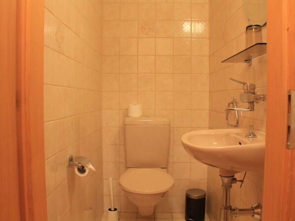 A small bathroom with a toilet, sink, and a toilet paper holder.
