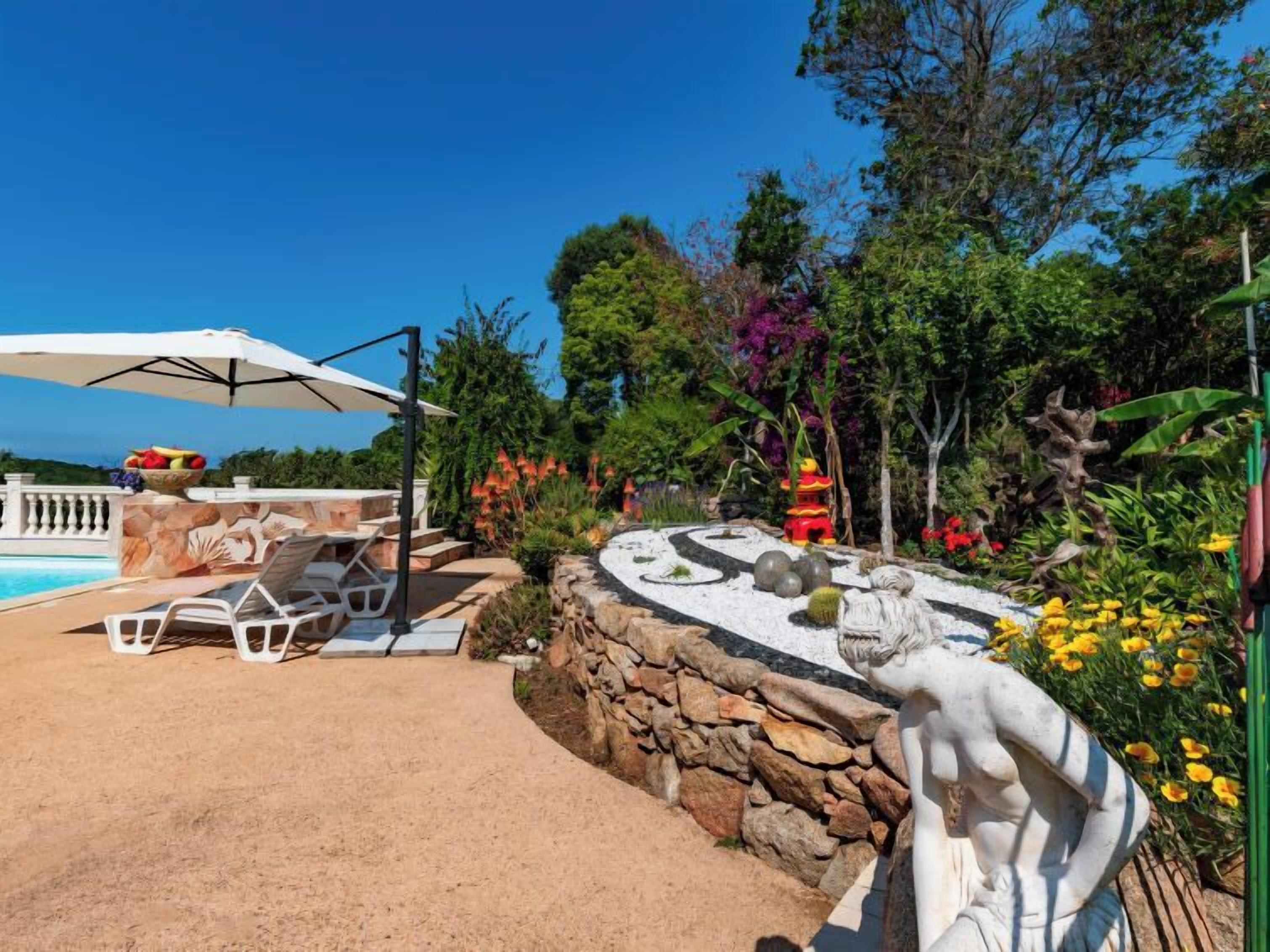 A pool area with lounge chairs and a statue.