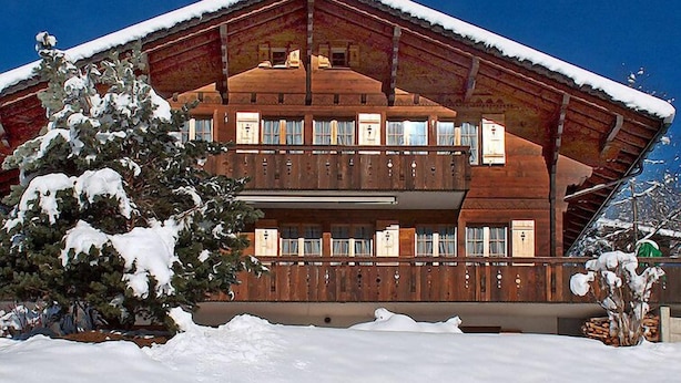 A two-story wooden chalet with a sloped roof, surrounded by snow. - Chalet Doris by Interhome (Grindelwald)