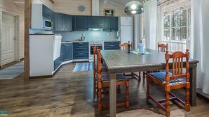 Una cocina amplia con armarios de madera, una isla central y un comedor con sillas y mesa de madera.