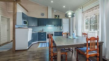 A spacious kitchen with dark blue cabinets, a wooden dining table, and a large window providing natural light.