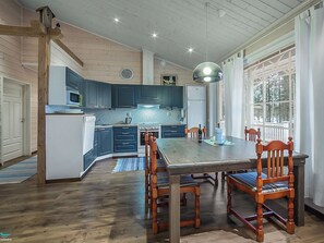Una cocina amplia con armarios azul oscuro, una mesa de comedor de madera y un ventanal que proporciona luz natural.