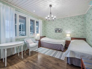 A bedroom with two beds, a small table, a chair, and a chandelier. - Villa kantri by Interhome (Multia)