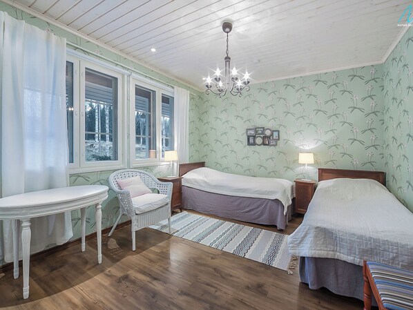 A bedroom with two beds, a small table, a chair, and a chandelier. - Villa kantri by Interhome (Multia)