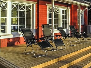 A wooden deck with four black lounge chairs aligned in a row. - Villa kantri by Interhome (Multia)