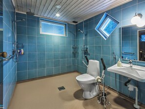 A bathroom with blue tiles, a toilet, a sink, and a shower. - Villa kantri by Interhome (Multia)