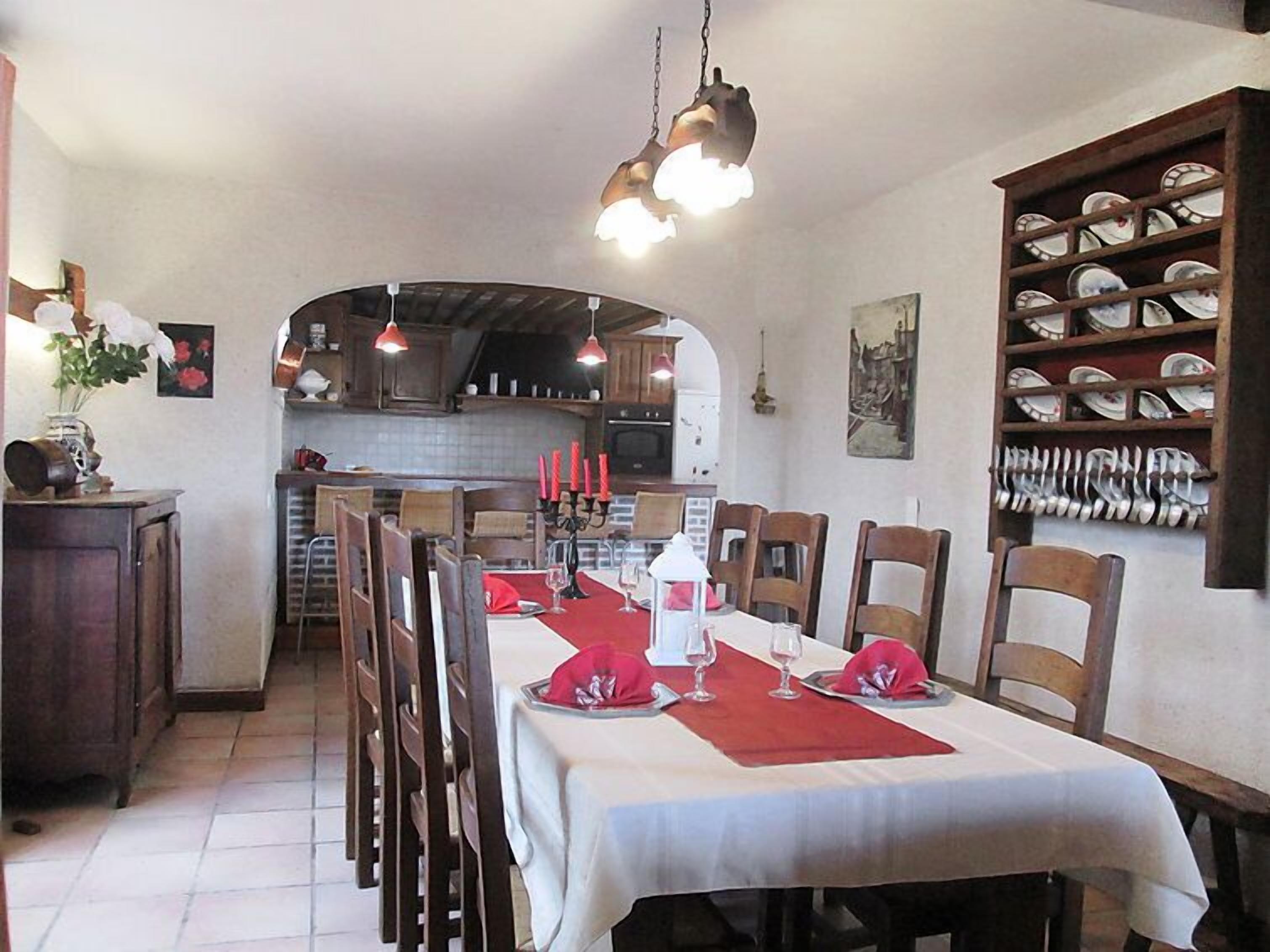 A dining area with a long table set for six, surrounded by wooden chairs. There are hanging pendant lights above the table.