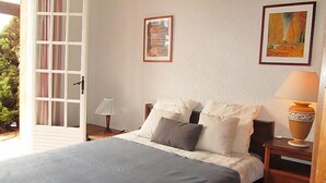 Ein Schlafzimmer mit einem Bett, Nachttischen, einer Lampe und zwei gerahmten Bildern an der Wand.