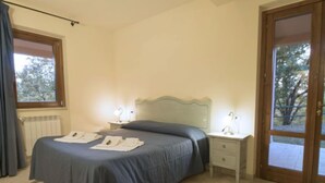 A bedroom with a bed, bedside tables, a window, and a door. - Thermae Villa 34 by Interhome (Pitigliano)