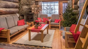 L’intérieur chaleureux d’un chalet en bois, avec une cheminée en pierre, des meubles en bois et un sapin de Noël.