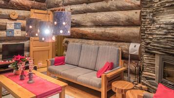 Ein gemütliches Blockhaus-Interieur mit einer Couch, einem Holztisch und einem Kamin.