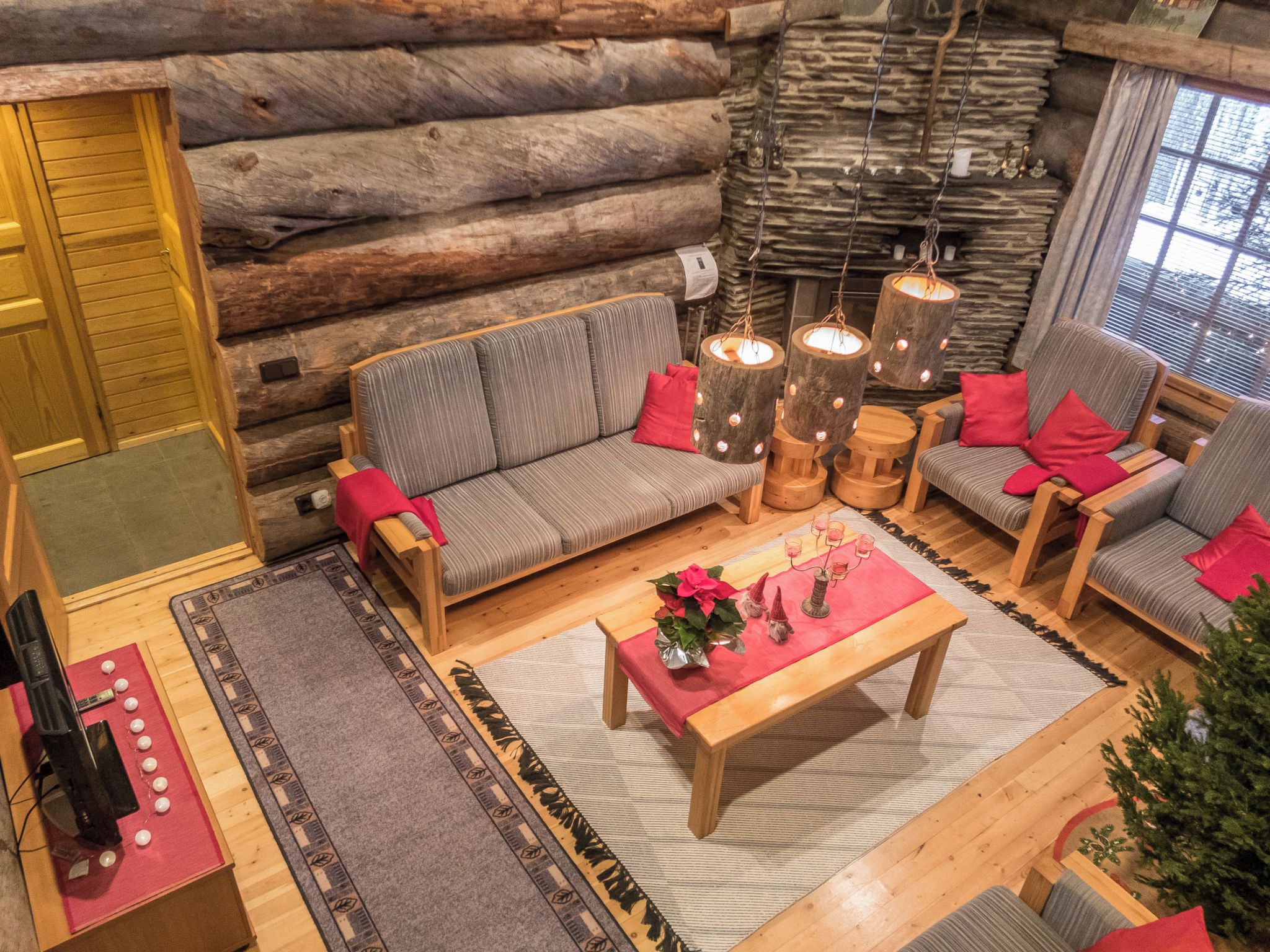 Interno di una baita di legno con un divano, poltrone, un tavolino da caffè e un camino.