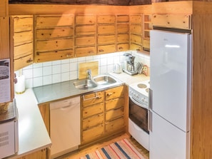 Une cuisine compacte avec des meubles en bois, un lave-vaisselle Bosch, un réfrigérateur blanc et une machine à café.