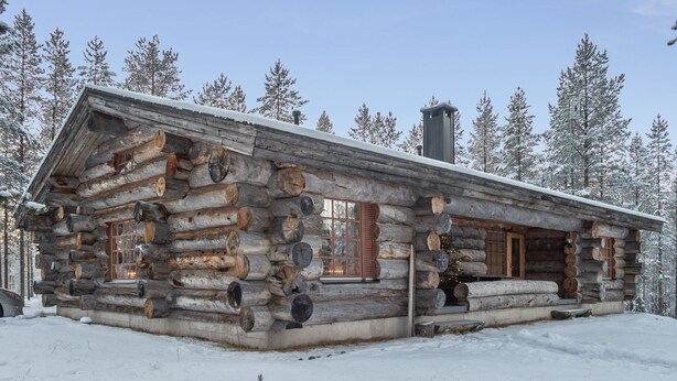 Une cabane en rondins avec une cheminée, une véranda et une fenêtre.