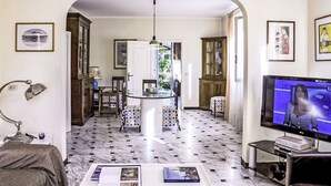 Un salon comprenant un téléviseur, une table basse avec des livres, un canapé et un coin repas avec des chaises et une table.
