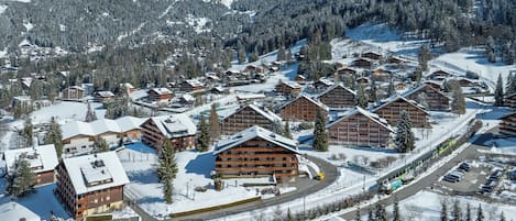 Estância de montanha coberta de neve, com cabanas de madeira, pistas de esqui e um céu limpo.