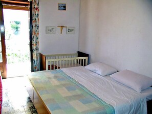 A bedroom with a bed, a crib, and a door leading to a balcony. - Apartment Zdenko by Interhome (Ugljan/Kali)