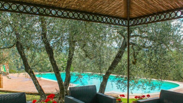 An outdoor seating area with wicker furniture, overlooking a swimming pool.