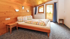 Une chambre confortable avec un plafond en bois, un lit avec une literie à rayures, une petite table de chevet et une fenêtre avec des rideaux.