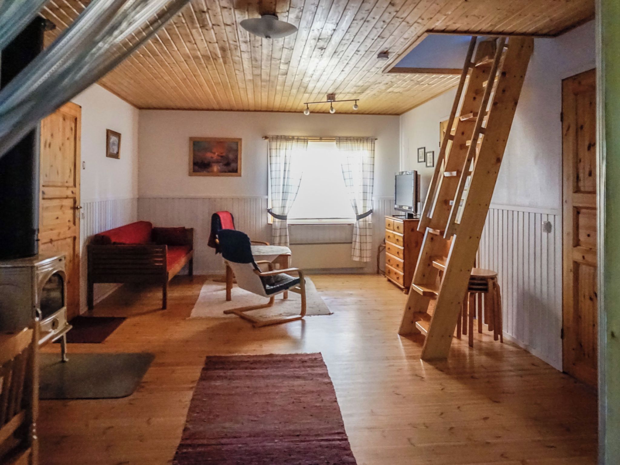 Una habitación con cama doble superior, escritorio, silla, televisor y escalera.