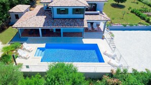 Une grande maison avec une piscine, de nombreuses pièces et un jardin.