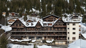 Una casa de montagna de diversos pisos amb balcons, arquitectura de fusta i entorns coberts de neu.