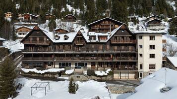 Eine mehrstöckige Lodge mit Balkonen, Holzbauweise und verschneiter Umgebung.