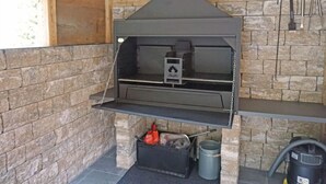 Een stenen muur met een ingebouwde barbecue en schoorsteen.