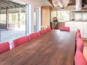 Une cuisine moderne avec une grande table en bois et des chaises recouvertes d’un tissu rose.