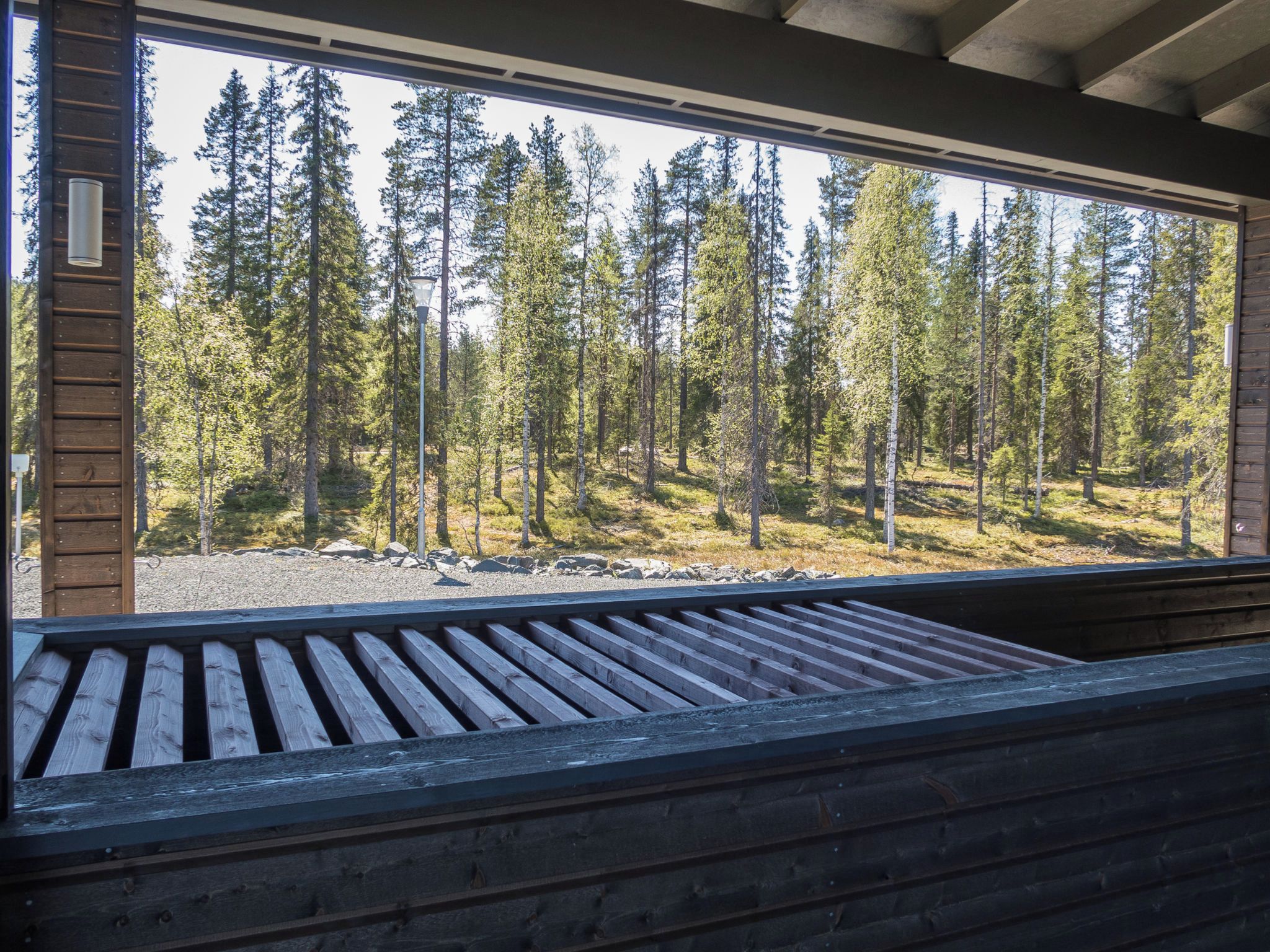 A wooden bench with a view of a forest through a large window.