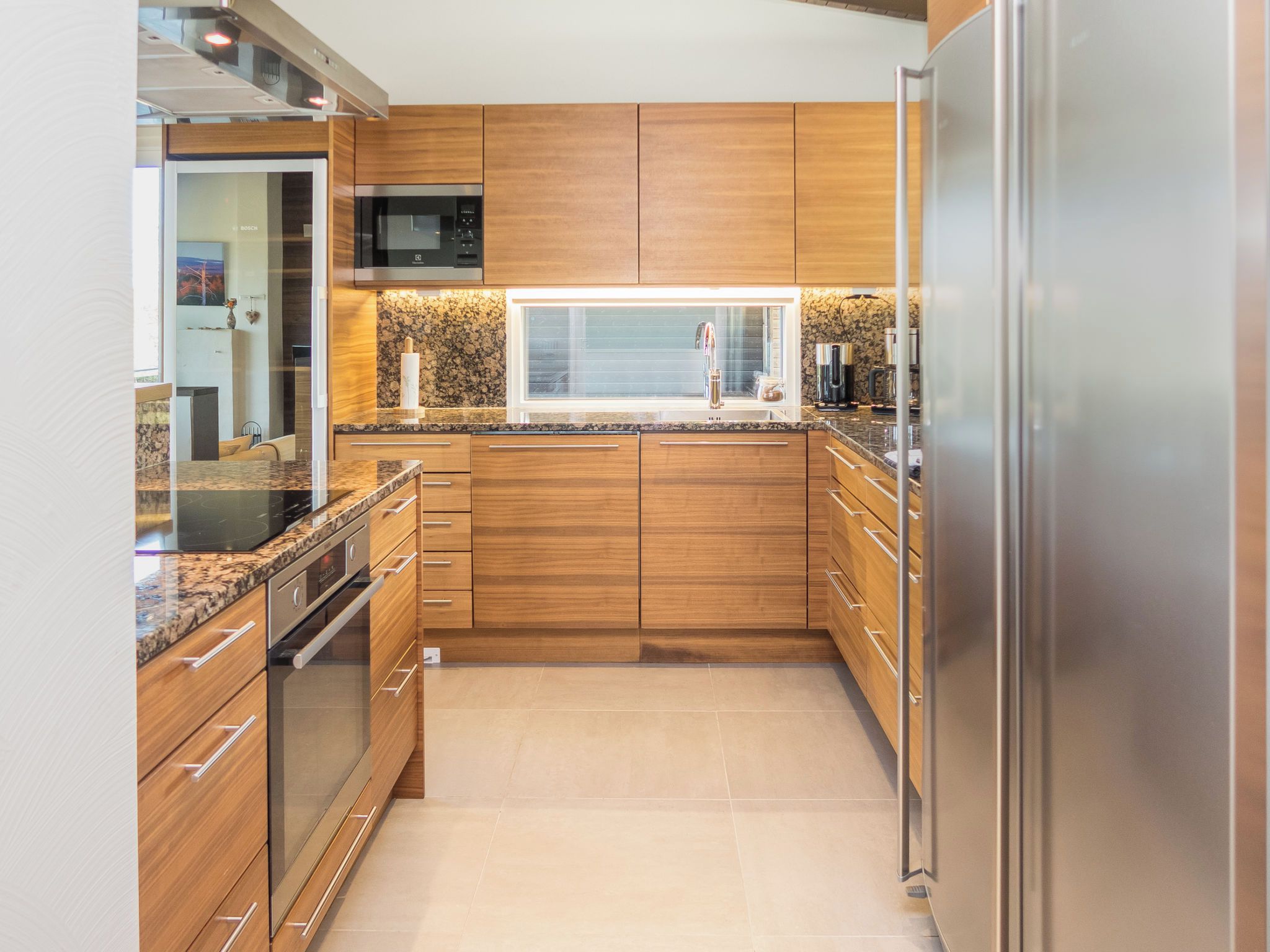 A modern kitchen with wooden cabinets, stainless steel appliances, and a granite countertop.