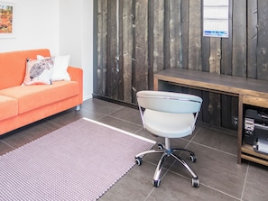 A modern office space with a bright orange sofa, a white office chair, a wooden desk, and a tiled floor. - Holy lake chalet b by Interhome (Kuusamo)