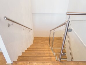 A wooden staircase with metal handrails and glass panels.