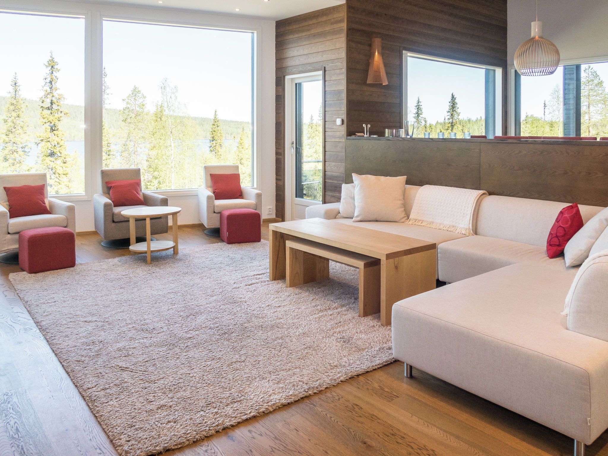 Ein modernes Wohnzimmer mit einem großen Sofa, zwei Sesseln, einem Couchtisch und einem Teppich.